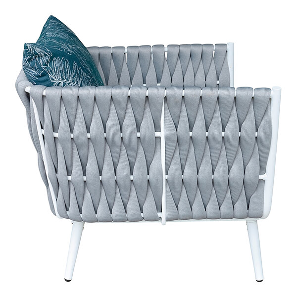 A white wicker outdoor armchair with grey rope and blue Sunbrella cushions and back pillow.