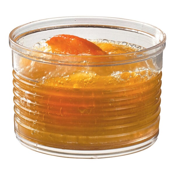 A Solia clear plastic tin can filled with yellow liquid and ice with an orange slice.