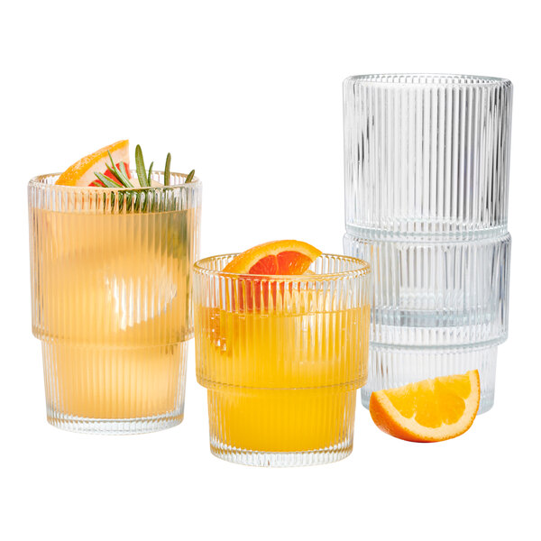 A stack of Anchor Hocking beverage glasses filled with orange juice and garnished with orange slices.