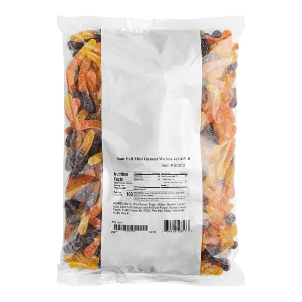 A large clear plastic bag filled with assorted mini sour gummy worms in fall colors.