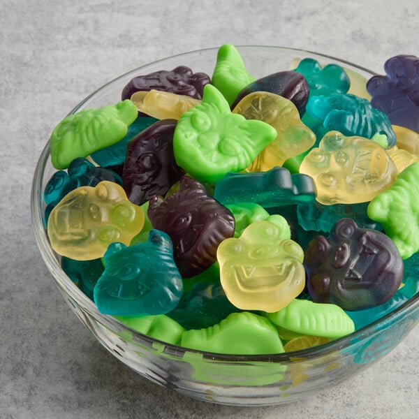 A glass bowl filled with assorted colorful gummy candies shaped like monsters.