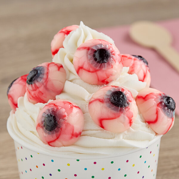 A cup of whipped cream topped with several Vidal gummy eyeball candies.