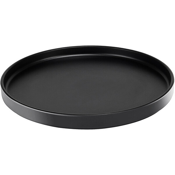 A black round Cal-Mil low rim melamine plate on a counter.