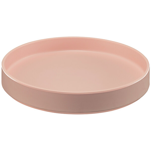 A pink round Cal-Mil Hudson melamine plate with a raised rim on a table.