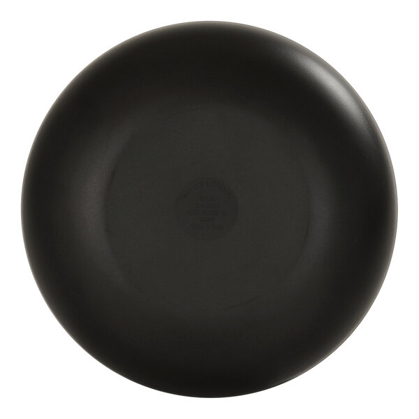A black round pasta bowl with an ivory interior and a circular logo on the ivory surface.