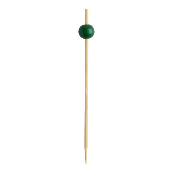 A bamboo cocktail pick with a green ball decoration near the top.