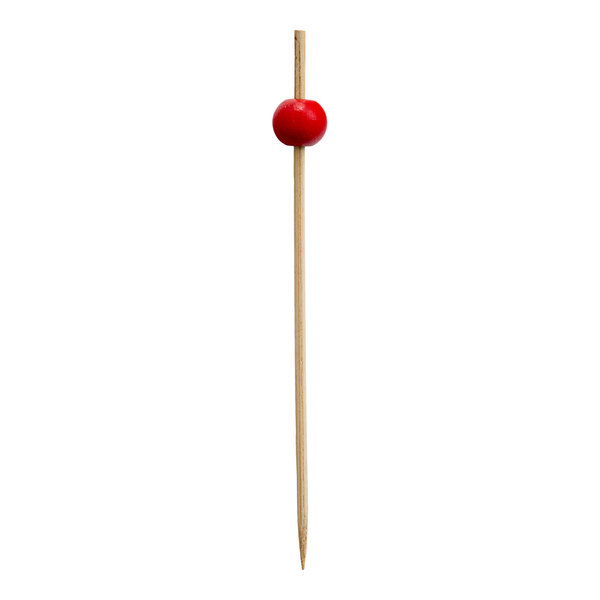 A bamboo cocktail pick with a red ball decoration near the top.