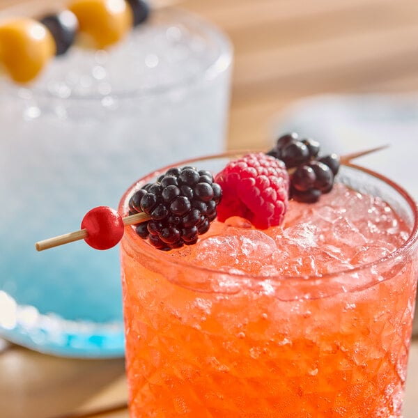 A red ball bamboo cocktail pick garnished with berries, placed on a glass of iced beverage.