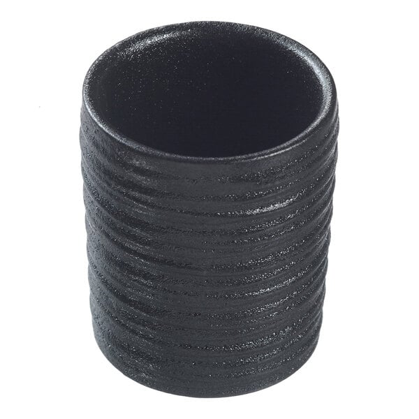 A black cylindrical Solia porcelain dish with textured ribbed lines.