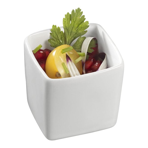 A white square Solia mini dish with vegetables and a yellow tomato.