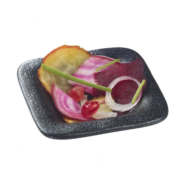 A Solia black porcelain square mini dish with food on it.