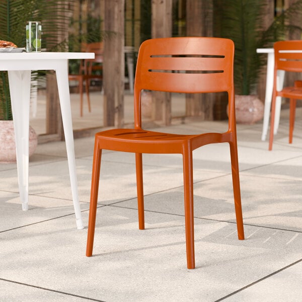 A terracotta-colored resin side chair with a slat back design.
