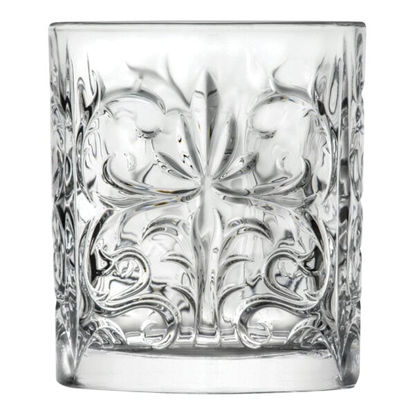 A clear, intricately patterned rocks glass with a floral and scroll design.