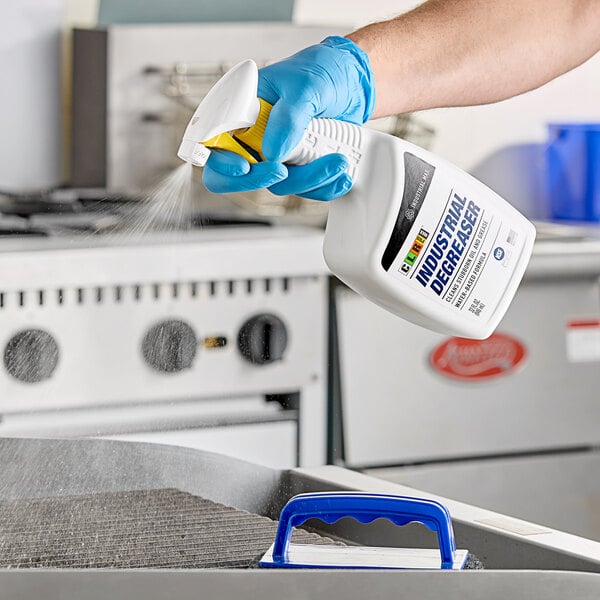 A person in blue gloves spraying CLR Pro Max Industrial Degreaser on a professional kitchen counter.
