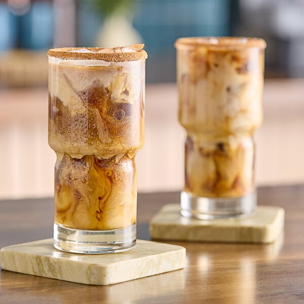 A glass of brown almond milk on a wooden coaster.