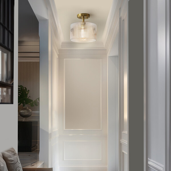 A semi-flush mount ceiling light with a matte brass base and a clear ribbed glass shade.