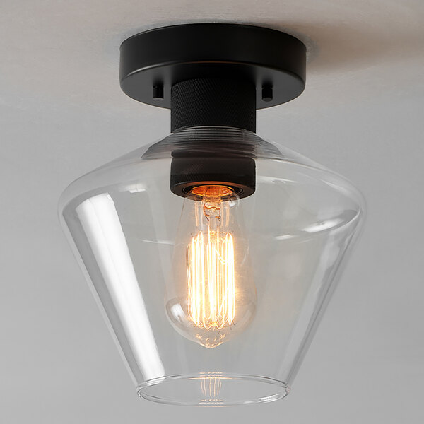 A semi-flush mount ceiling light with a matte black base and a clear glass shade.