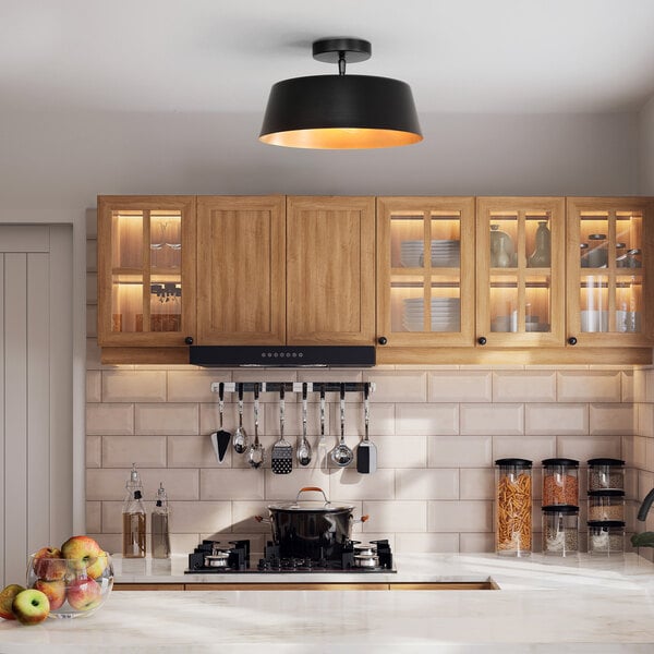 A matte black flush mount ceiling light with a painted gold interior shade.