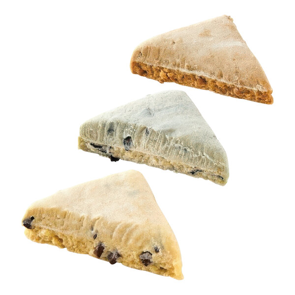 A close up of a triangular scone with raisins and nuts.