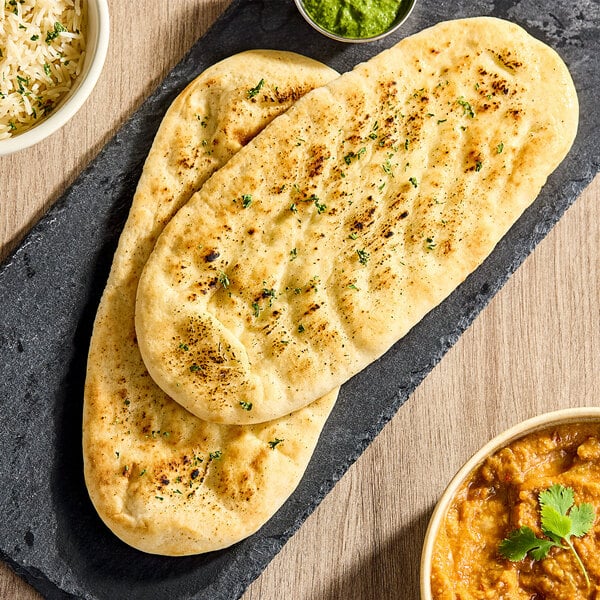 A pair of tandoori naan breads displayed on a black serving tray.