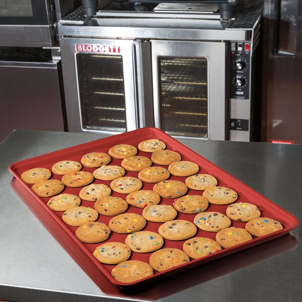 A red MFG Tray market display tray with cookies on a counter.