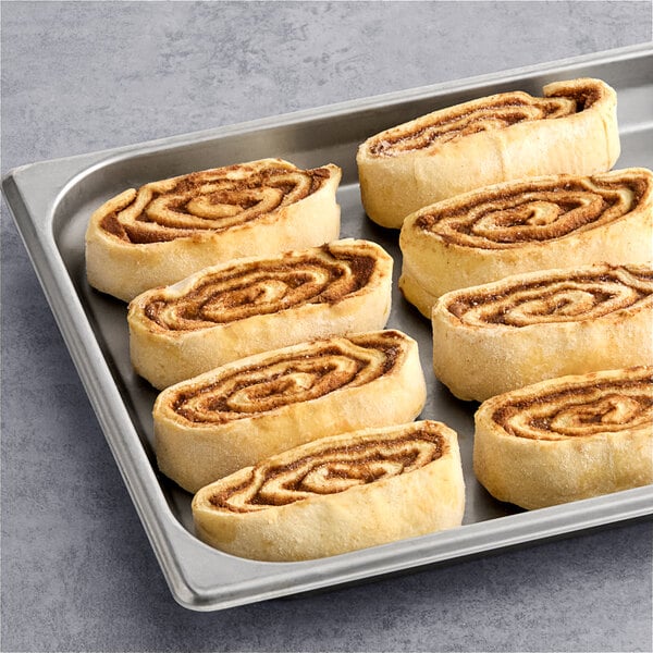 Pillsbury Plus Frozen Cinnamon Roll Dough in a pan with six cinnamon rolls on it.