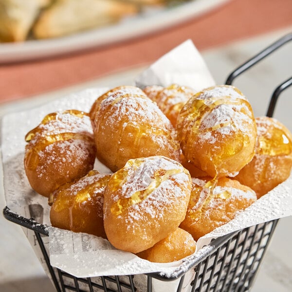 A basket of Kontos International Pastry Puffs on a table with powdered sugar.