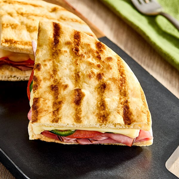 A pre-grilled panini sandwich made with Kontos 8-inch panini bread, filled with deli meat, cheese, and vegetables.