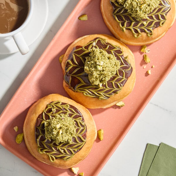 A plate of Kontos kataifi pastries with green toppings on a table.