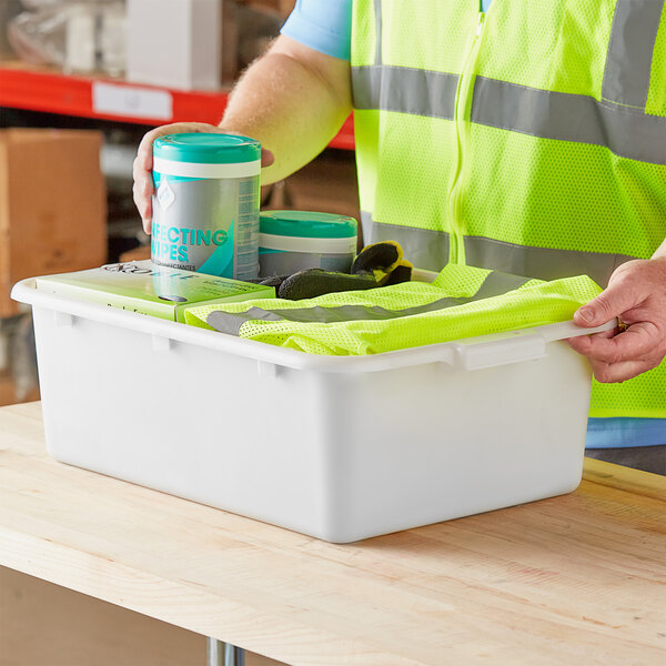 A white polypropylene utility bin containing cleaning supplies and a safety vest.