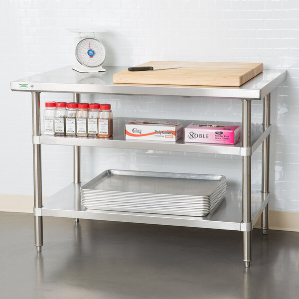 A stainless steel adjustable undershelf attached to a 24-inch by 48-inch work table, used for additional storage in a kitchen setting.