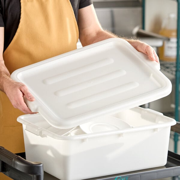 A white polyethylene utility lid being placed on a rectangular storage container.