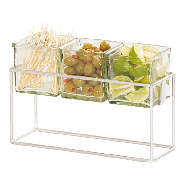 A Cal-Mil chrome condiment display with 3 square glass jars holding fruit.
