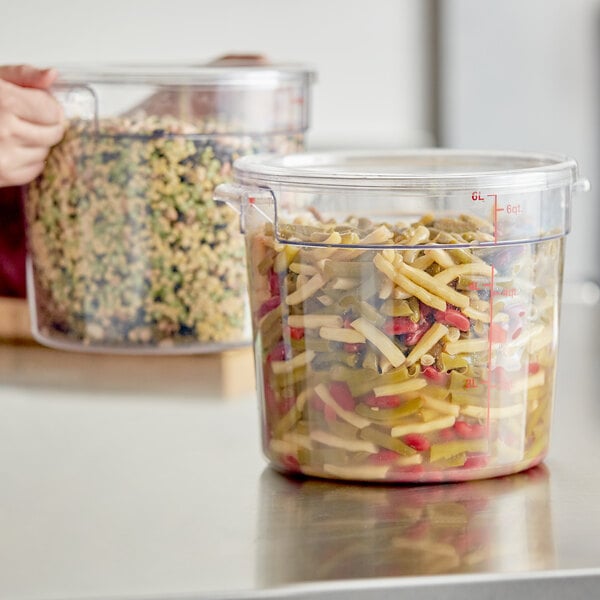A clear round polycarbonate food storage container with a lid, filled with mixed vegetables.