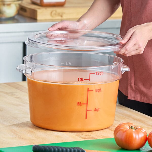 A clear round polycarbonate food storage container with a lid and red measurement markings, holding up to 12 quarts.