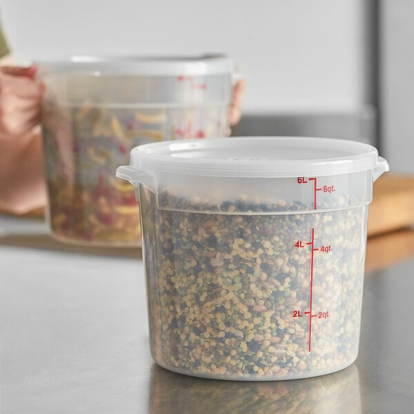 A translucent 6-quart round polypropylene food storage container with a lid and red measurement markings.