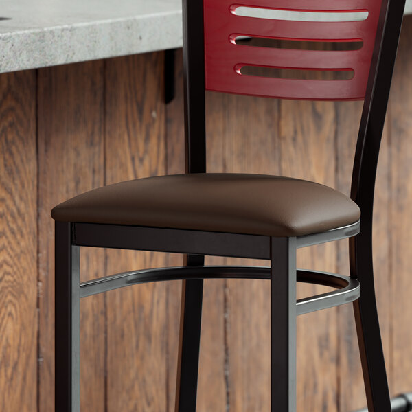 A Lancaster Table & Seating dark brown vinyl padded seat on a metal frame chair at a bar counter.