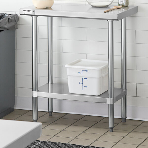 A stainless steel work table with an adjustable undershelf, shown with a white storage container placed on the lower shelf.