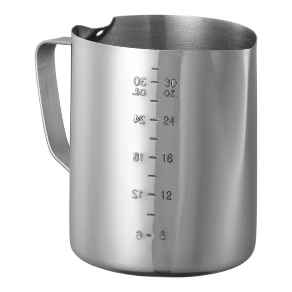 A stainless steel Service Ideas frothing pitcher with measuring lines and a handle.