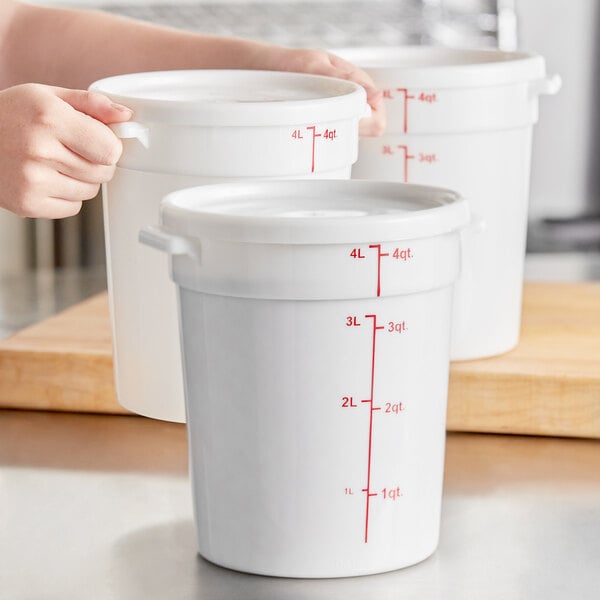 A set of white round polypropylene food storage containers with lids and red measurement markings.