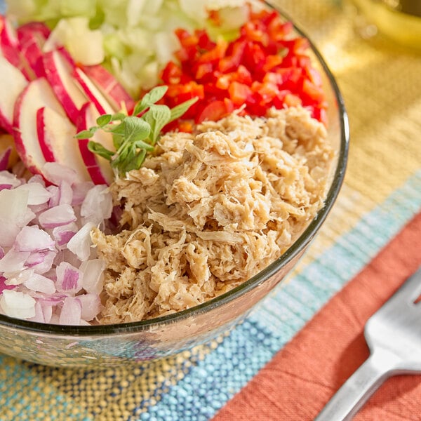 A glass bowl filled with plant-based vegan spicy tuna, chopped onions, radishes, celery, and red bell peppers.