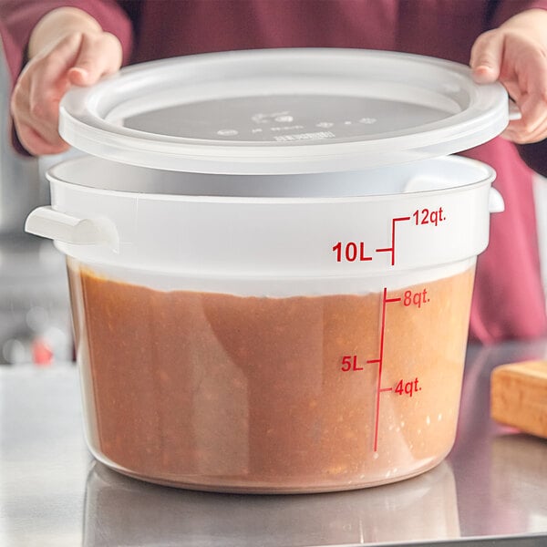 A large translucent round polypropylene food storage container with a lid and red measurement markings.
