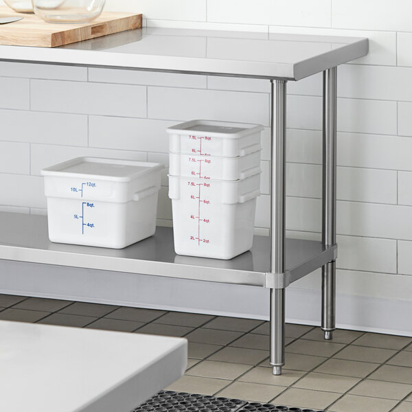 An adjustable stainless steel undershelf installed on a work table, holding several white food storage containers.