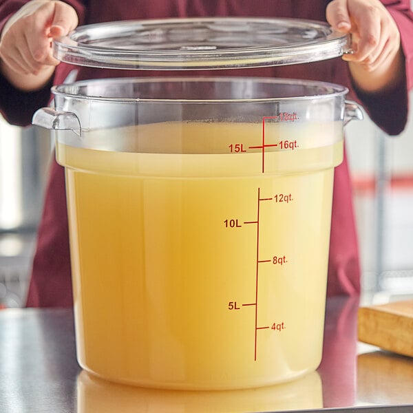 A clear round polycarbonate food storage container with a lid, filled with liquid and marked with measurement lines up to 18 quarts.