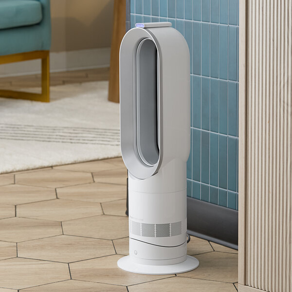 A black and nickel Dyson Hot+Cool fan and heater on a tile floor in a room with blue walls.