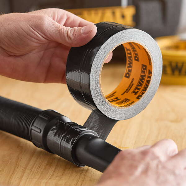 A roll of black DeWalt ultra-tough duct tape being applied to a hose connection.
