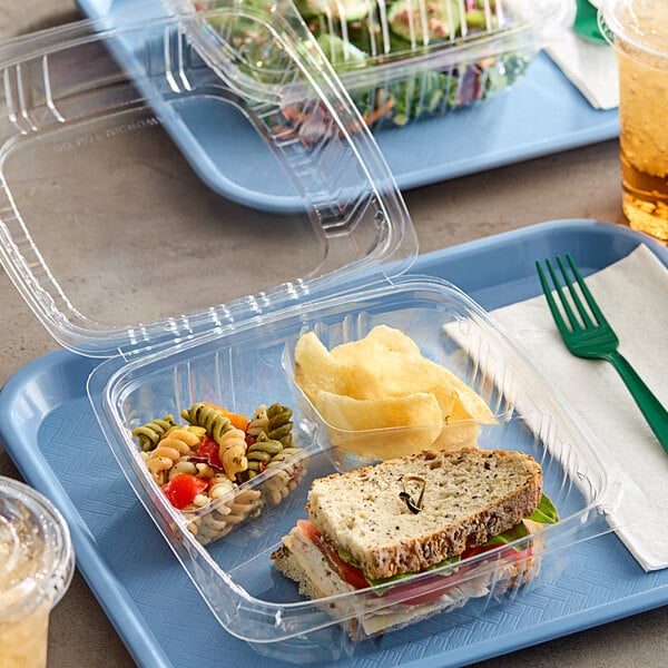 A Choice clear hinged plastic container with sandwich, salad, and bread.