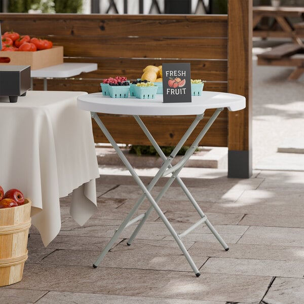 A 32-inch round granite white plastic folding table with gray legs.