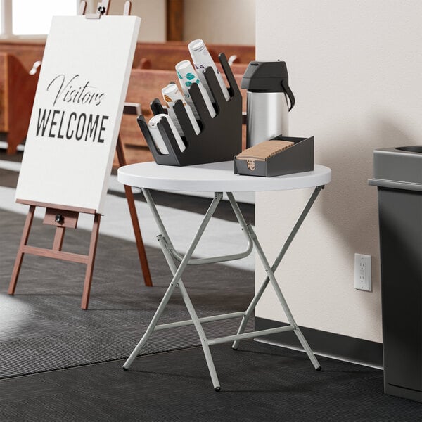 A round, granite white plastic folding table with gray metal legs.