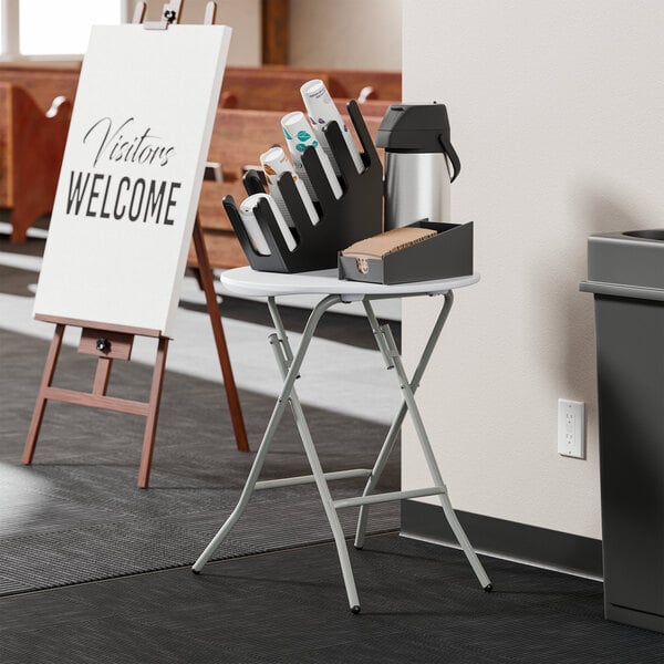 A round, granite white plastic folding table with gray legs, set up in a standard height position.